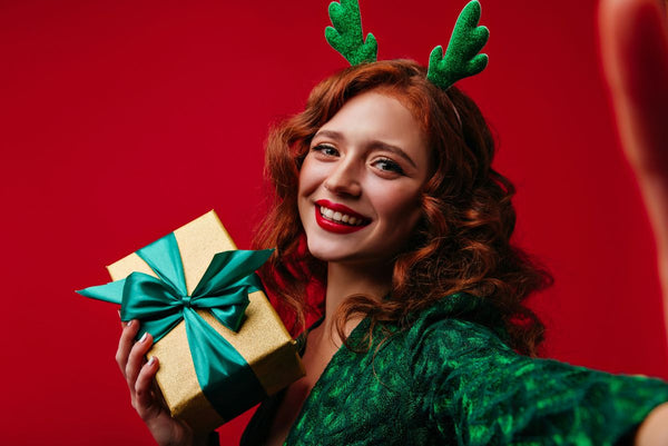 woman in a green dress holding a present wrapped in a green bow