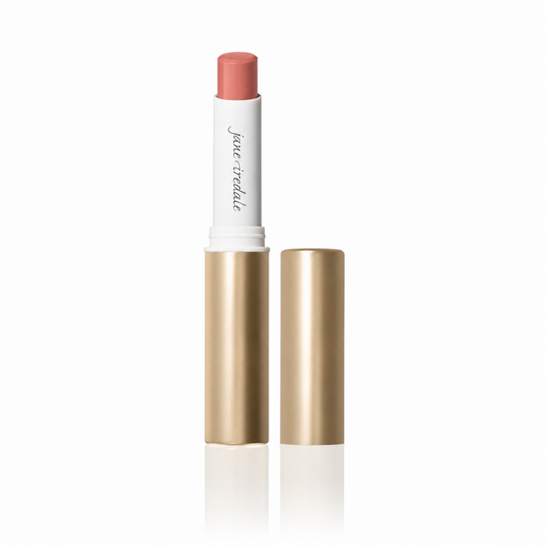 A tube of lipstick with its cap removed, standing upright on a white reflective surface. The lipstick bullet is a muted peach-pink, the inner tube is white with black script text reading 'jane teddie', and the outer casing is metallic gold.