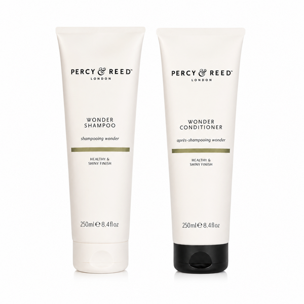Two white Percy & Reed London tubes, Wonder Shampoo and Wonder Conditioner, standing side by side on a white background.