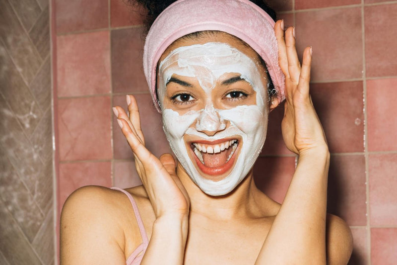 close up of girl smiling and wearing clay face mask 