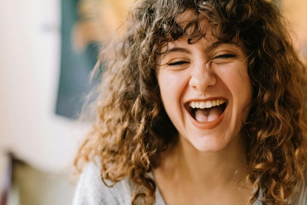 close up of woman with curly brown hair laughing