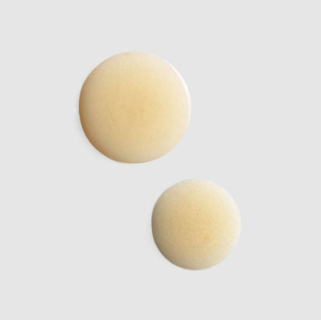 Pair of beige round earrings on a light gray background