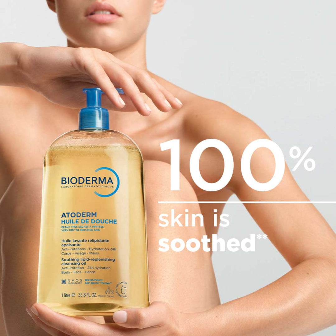 Bioderma shower oil bottle held by a person with text '100% skin is soothed' on a light gray background