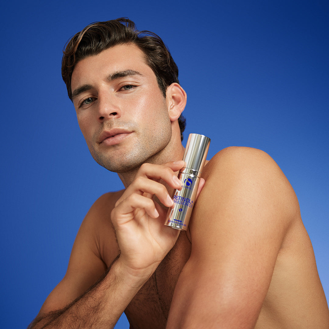 Man holding a skincare product against a blue background