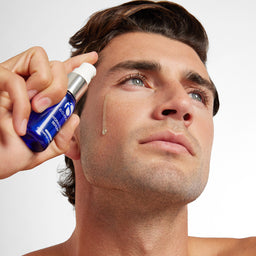 Man applying a skincare product to his face with a white background
