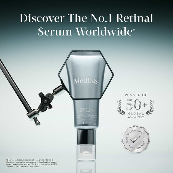 Medik8 Crystal Retinal 3 serum bottle shown on a gradient gray background with promotional text and award badges. A light stand is visible at left, and the bottle is centered with a reflective base.