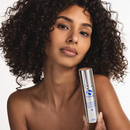 Woman holding a skincare product with a neutral background