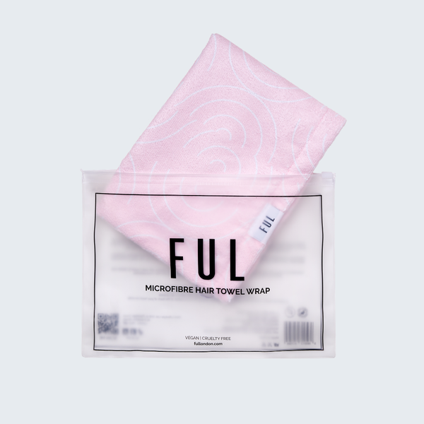 A folded light pink towel wrap with a subtle spiral pattern, partially pulled out of its clear plastic packaging. The packaging features a white label with black text reading 'FUL MICROFIBRE HAIR TOWEL WRAP'.