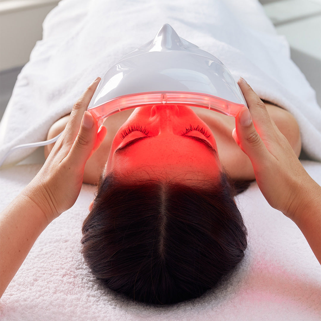 Person receiving a red light therapy treatment on their face.