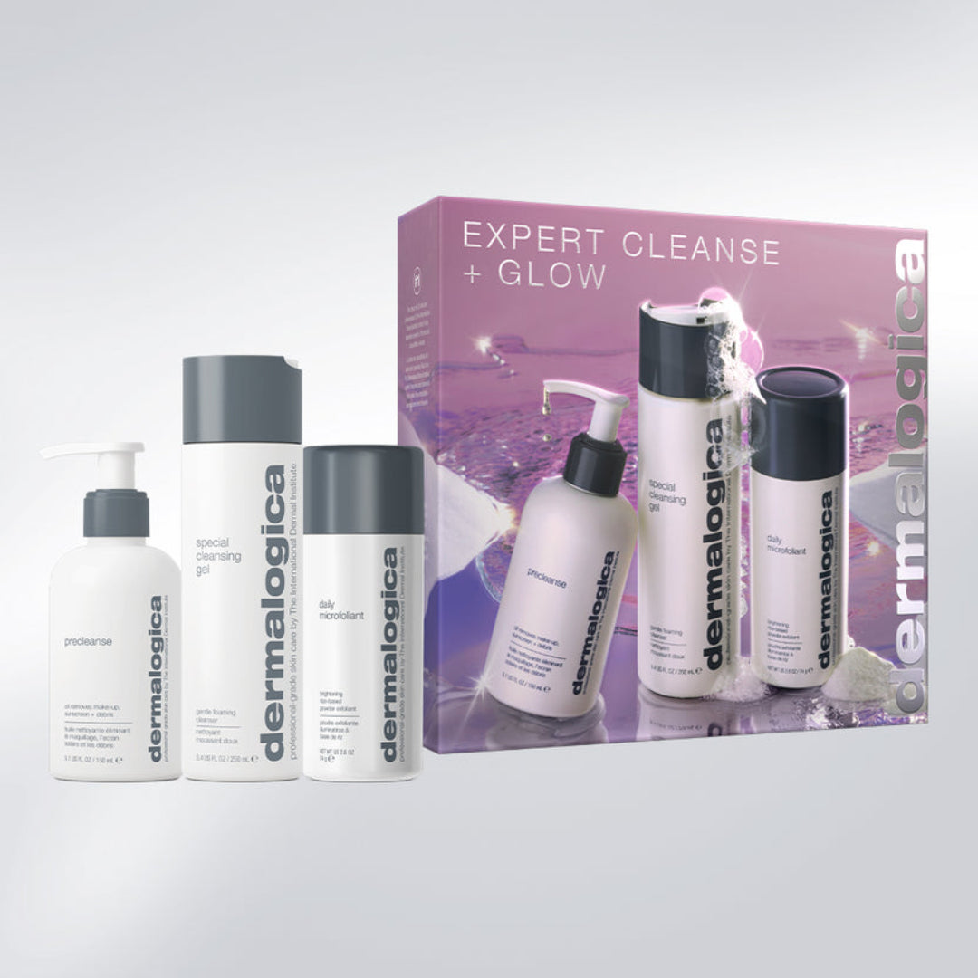 Dermalogica Expert Cleanse + Glow skincare set with four white bottles and a purple gift box on a light gray background.