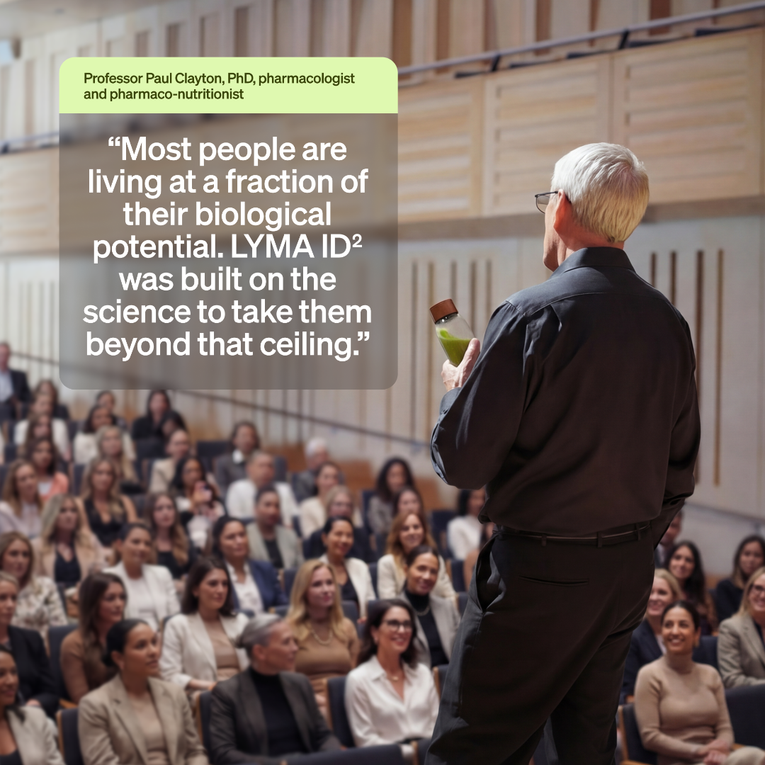 A man in a black shirt stands at the front of a lecture hall addressing a large audience, with a semi-transparent text box containing a quote attributed to Professor Paul Clayton, PhD.