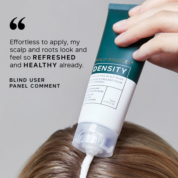 Hand applying a tube of Philip B Density Scalp Mask to hair with user feedback text.