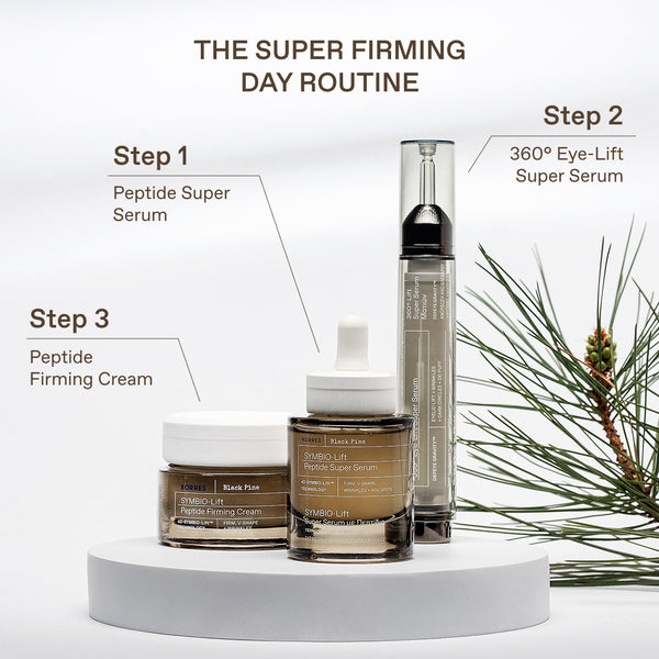Three skincare products from SKIN1005 are displayed on a white pedestal with instructional text labels for a 'Super Firming Day Routine' against a clean white background with pine branches.