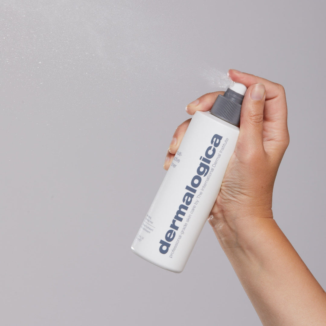 Hand holding a Dermalogica product against a gray background