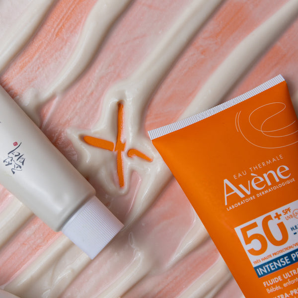 Two sunscreen products on a textured surface with a visible brand logo.