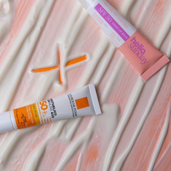 Two sunscreen tubes on a textured pink surface