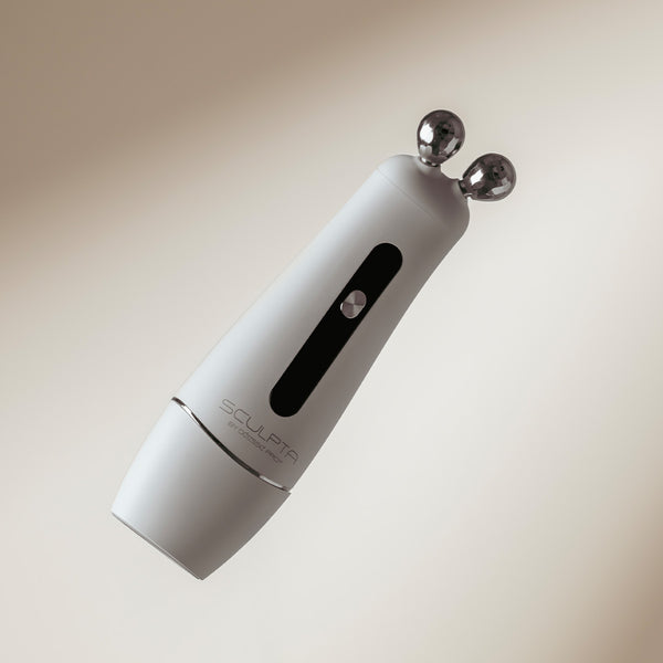 White handheld device with two metallic probes on a beige background