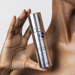 Hand holding a skincare bottle labeled 'NeckPerfect Complex' against a neutral background