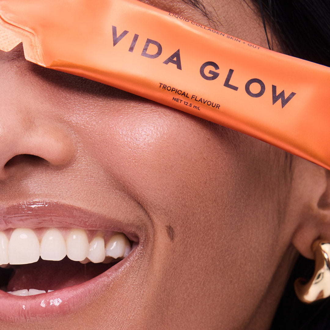 Close-up of a person wearing an orange 'Vida Glow' product on their face.