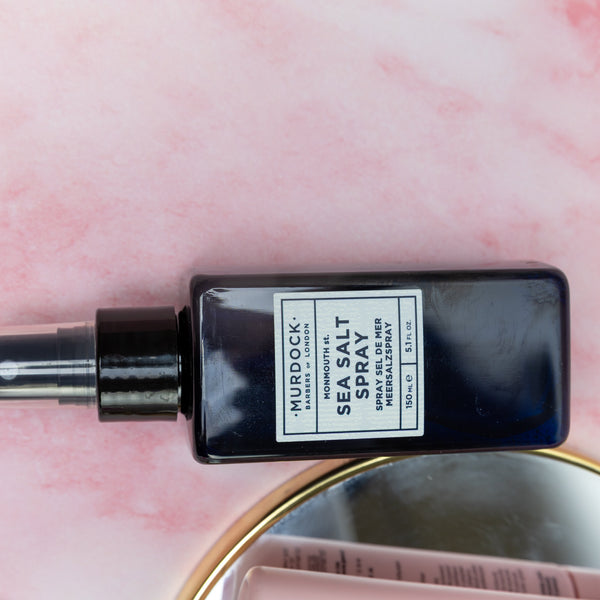 Black spray bottle labeled 'Hurdock' on a pink background