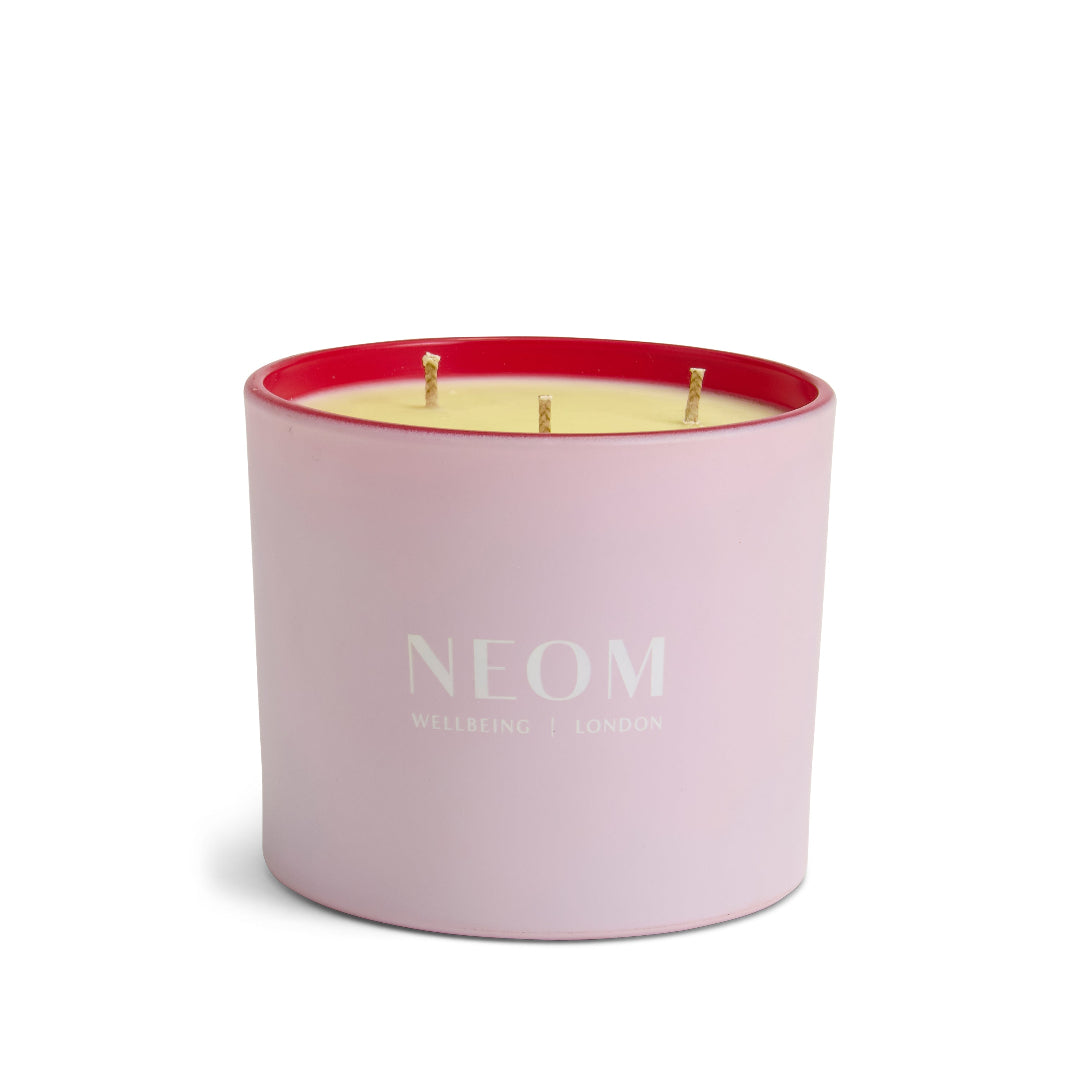 Pink candle with red interior and 'NEOM' branding on a white background