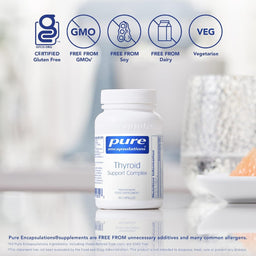 A white bottle of Pure Encapsulations Thyroid Support Complex dietary supplement centered on a reflective white surface, with certification icons for Certified Gluten Free, Free From GMOs, Free From Soy, Free From Dairy, and Vegetarian above it. The background is a softly blurred kitchen scene.