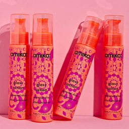 Four bottles of amika glass action product on a pink background