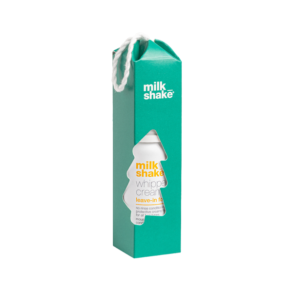 A tall teal-green Milk Shake leave-in whipped cream carton package with a white hanging loop and a die-cut window showing the product bottle inside, on a plain white background.