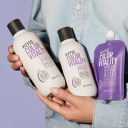 KMS Color Vitality hair care products held by a person against a purple background
