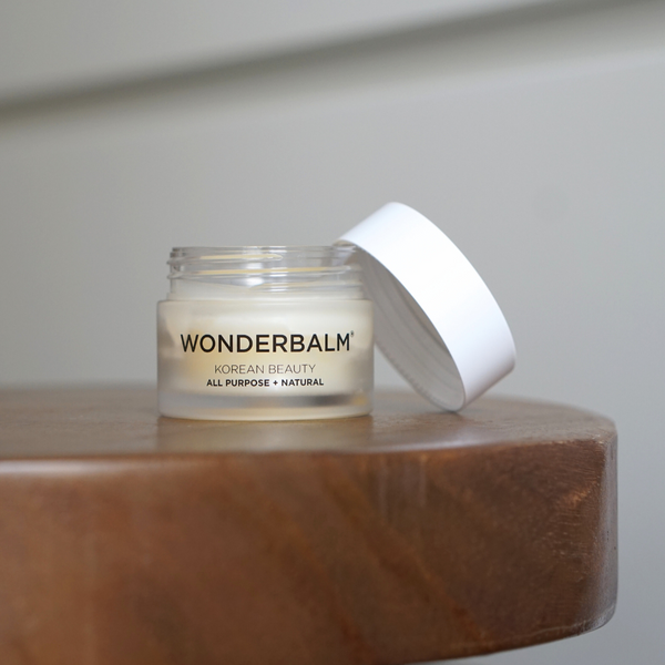 Jar of Wonderbalm on a wooden surface with a white background