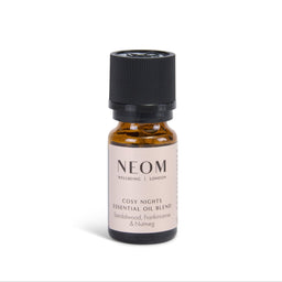 A small amber glass bottle of NEOM Wellbeing 'Cosy Nights' essential oil blend with a black cap and a beige label, set against a plain white background.