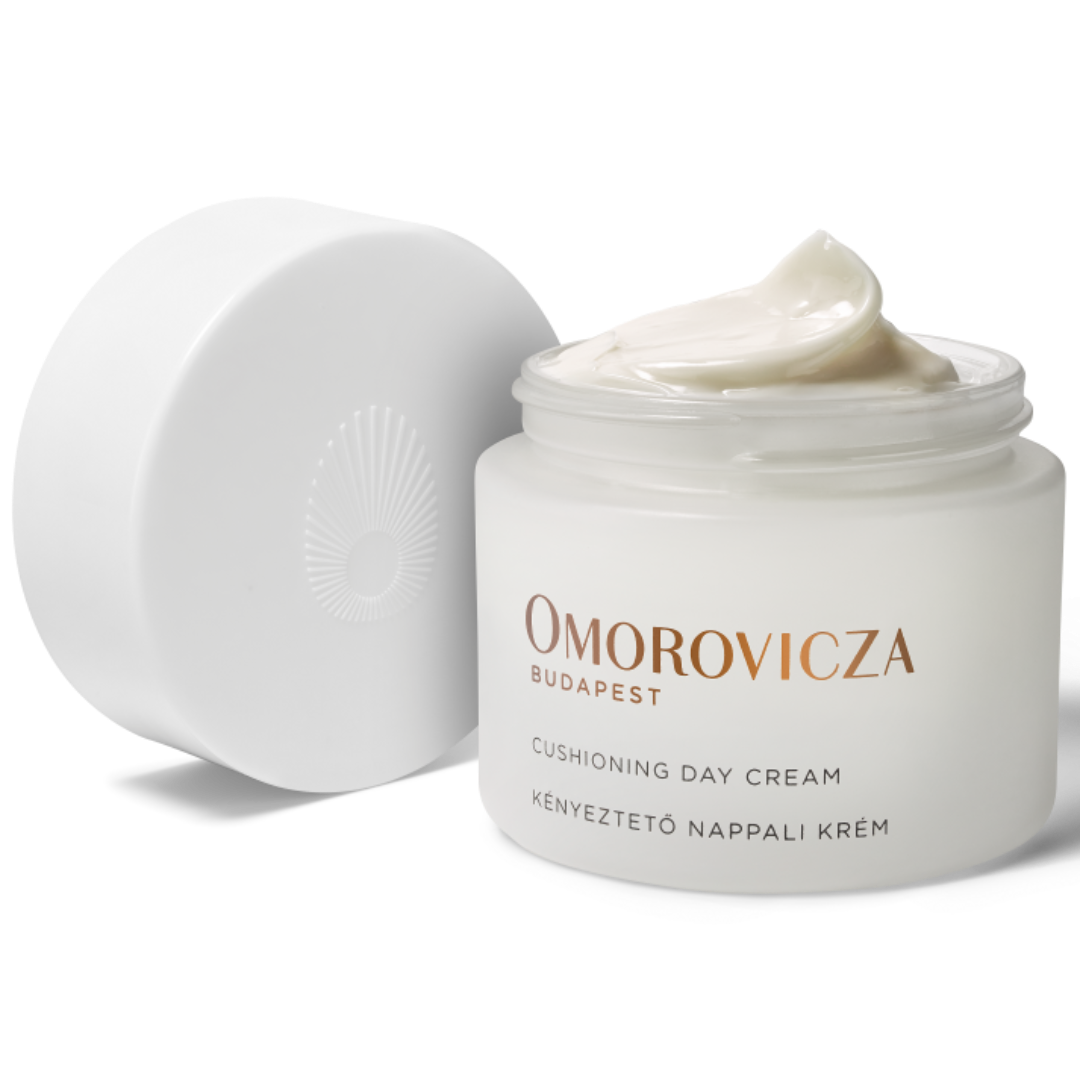 Omorovicza Cushioning Day Cream in a white jar with its lid off, showing a dollop of the cream on top, on a white background.