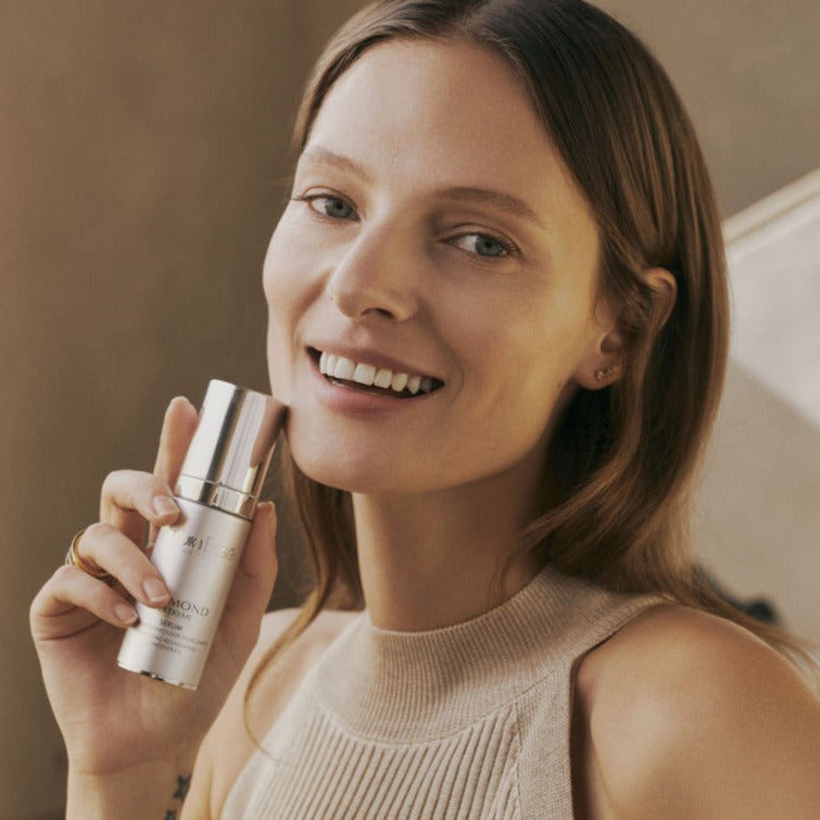 a model holding a bottle of Natura Bisse Diamond Extreme Serum close to her face