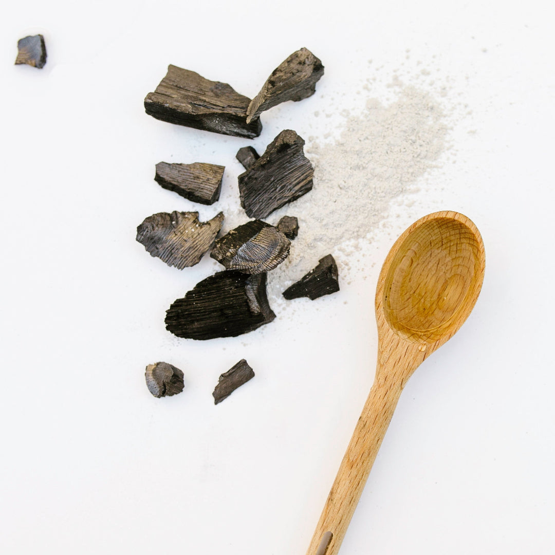 Black stone pieces and a wooden spoon on a white background
