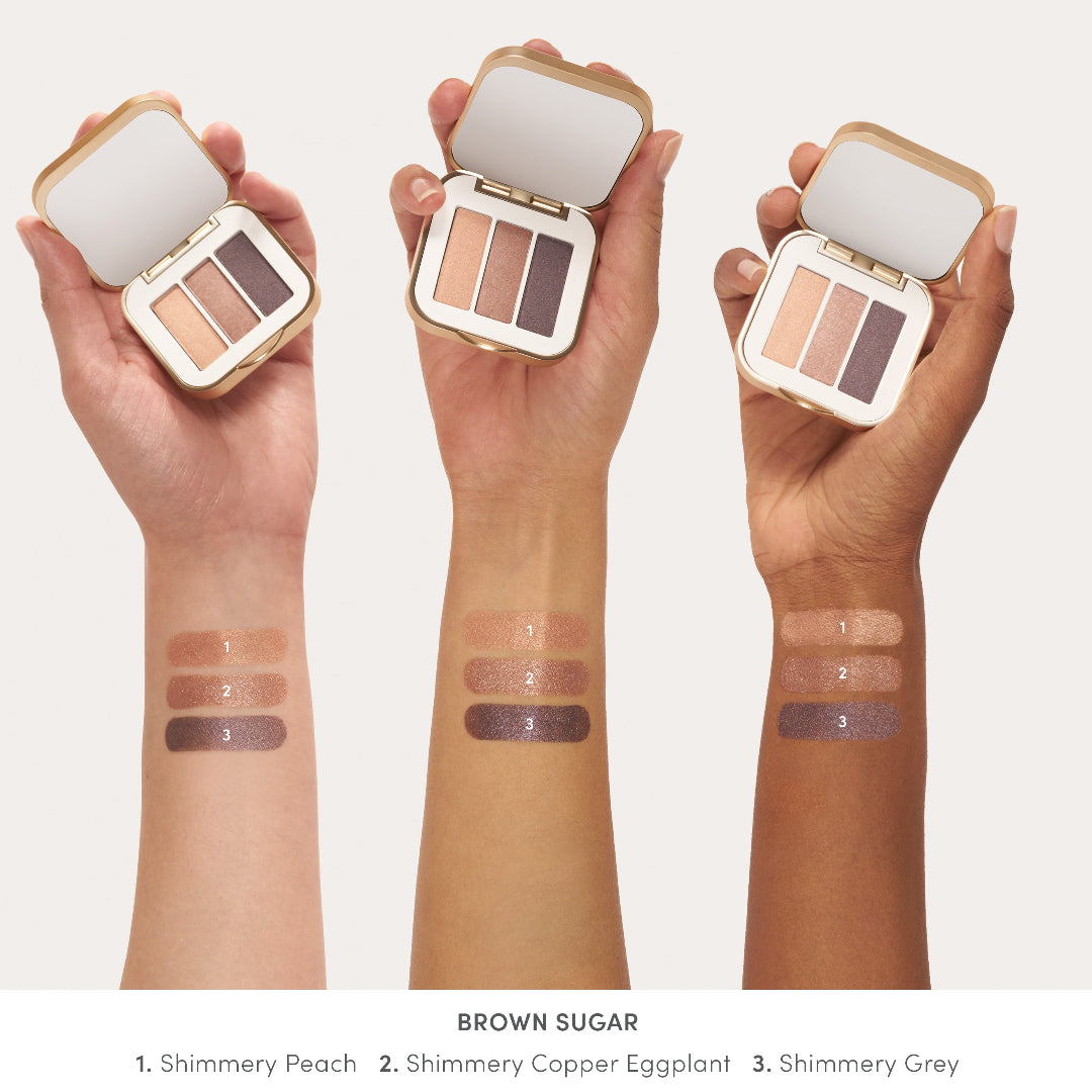 Three hands holding open makeup palettes with swatches on wrists, labeled 'Brown Sugar' with three shades.