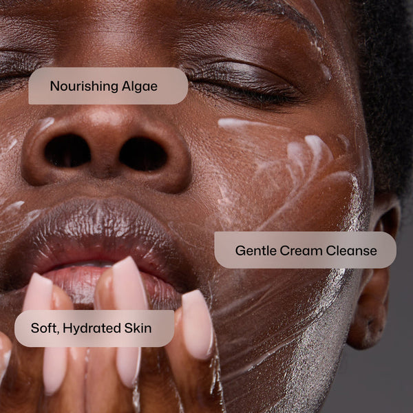 Close-up of a person's face with skincare labels overlaid: 'Nourishing Algae' on the forehead, 'Gentle Cream Cleanse' on the cheek, and 'Soft, Hydrated Skin' on the hand. The person has a dark complexion with white and silver skincare products visible on the skin.