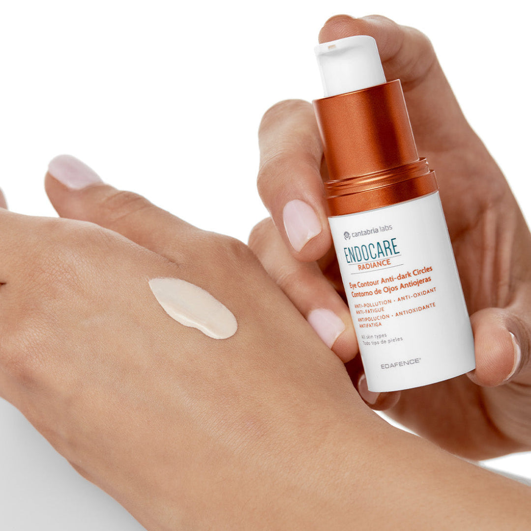 Hand holding a bottle of Enodocare skincare product with a swatch on skin.