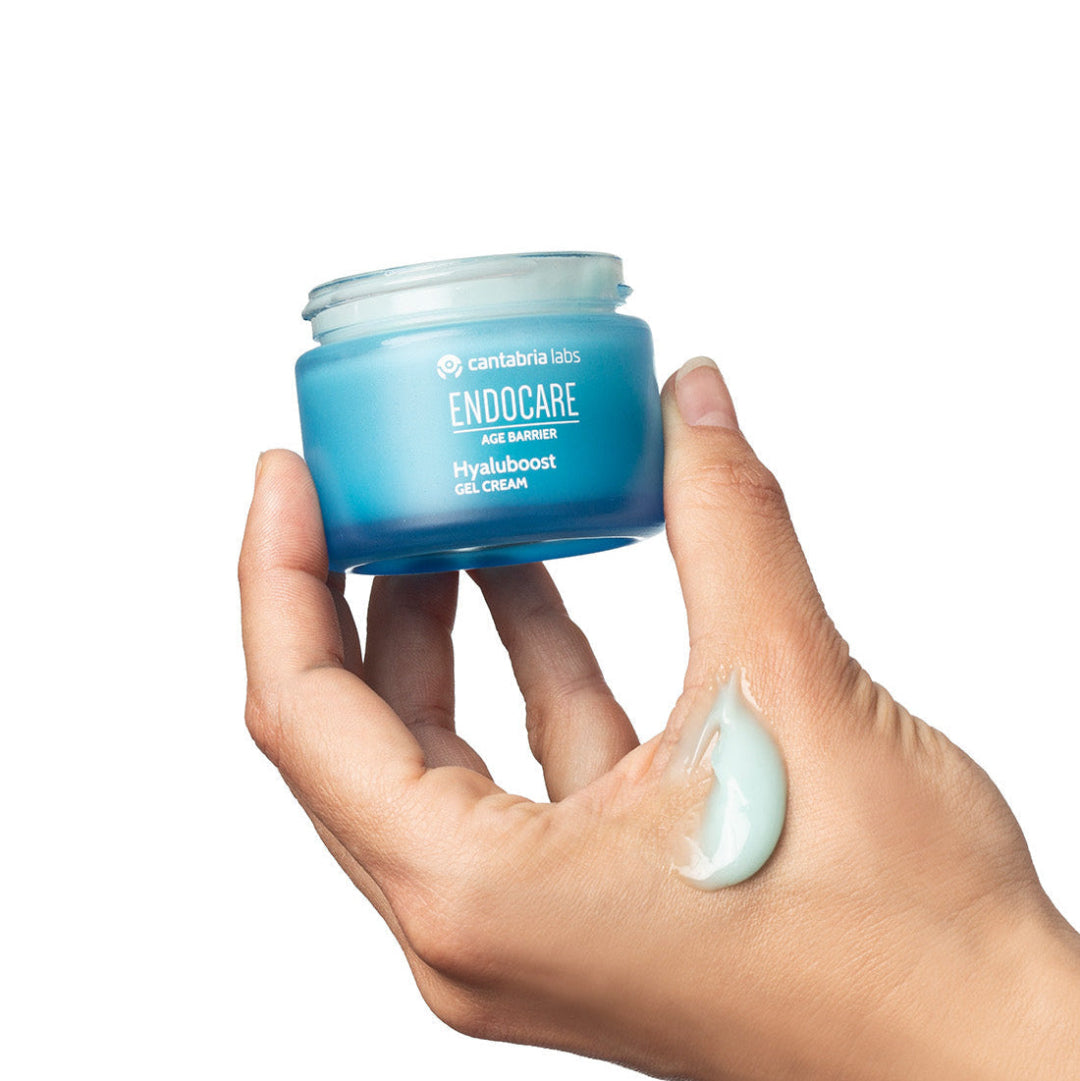 Hand holding a jar of Endocare cream with a white background