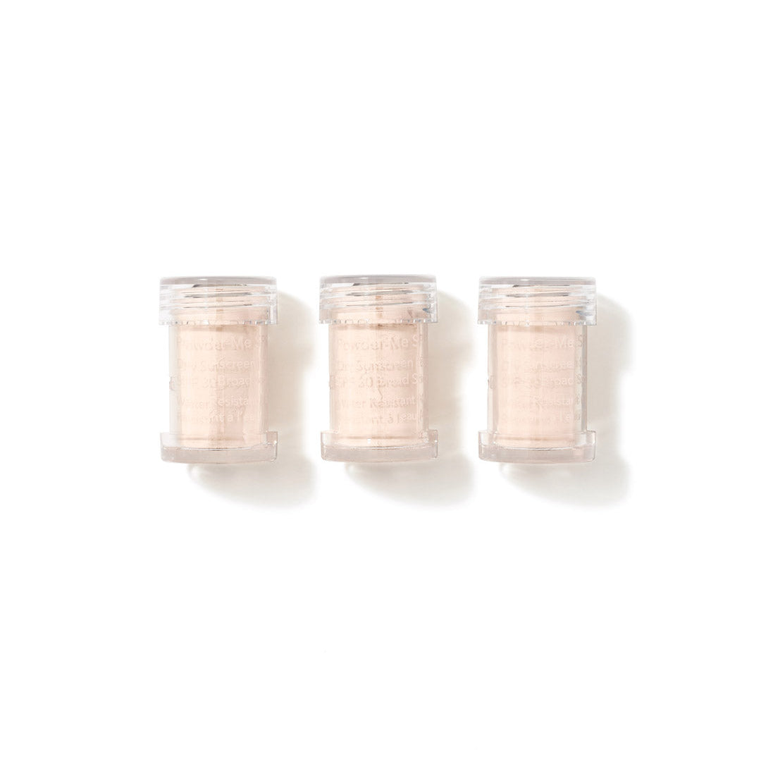 Three small clear plastic jars filled with a pale peach-beige textured powder, arranged side by side on a white background.