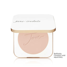 A Jane Iredale makeup compact with a white lid and a clear base showing a round blush or pressed powder in a light peach-beige shade. The compact has a thin metallic gold frame.
