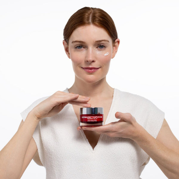 Woman holding two jars of skincare product against a white background