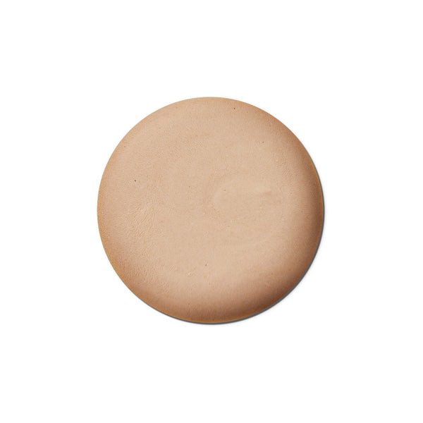 Round beige makeup compact on a white background