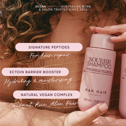 Person holding a NAK Hair shampoo bottle with product features displayed.