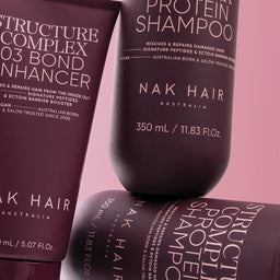 Nak Hair shampoo and conditioner bottles on a pink background