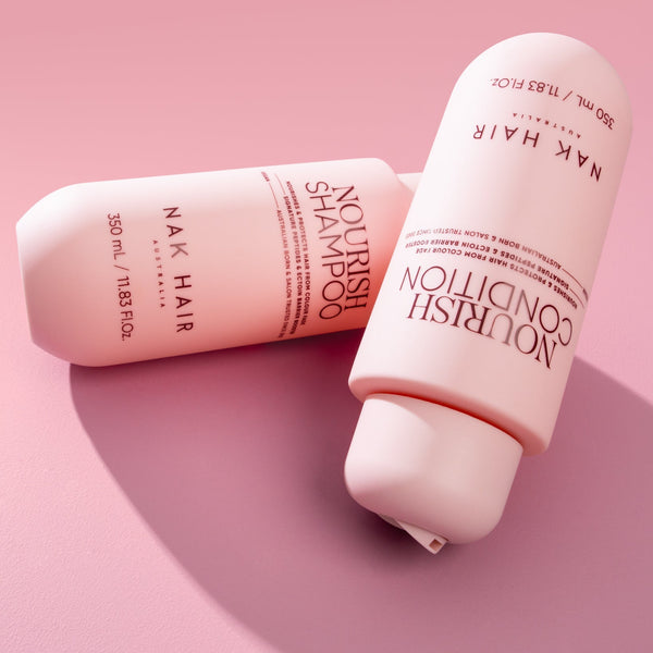 Nak Hair Nourish Shampoo and Conditioner bottles on a pink background