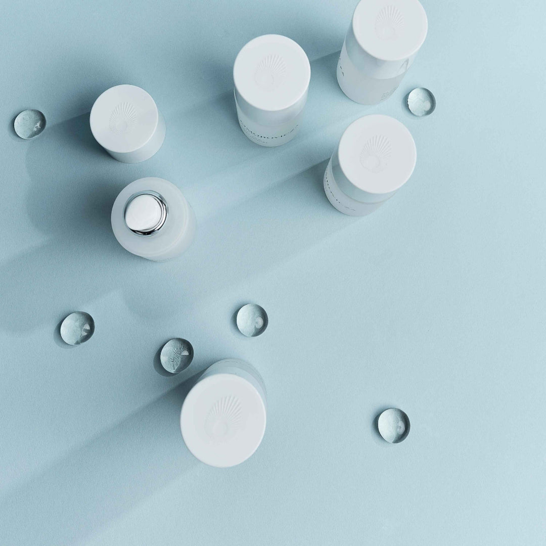 White cylindrical bottles with droplets on a light blue background