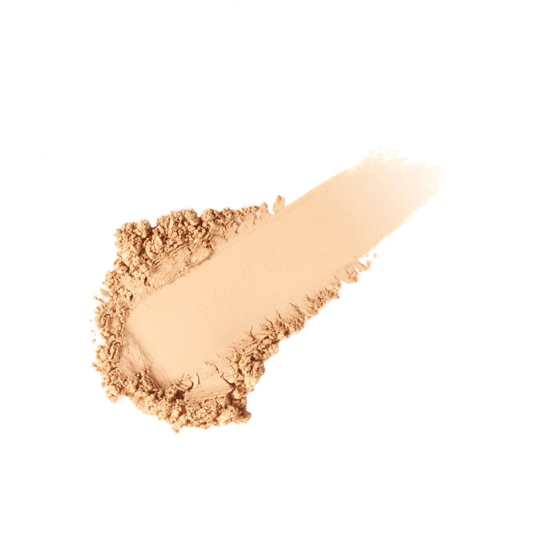 Beige makeup powder on a wooden spatula against a white background