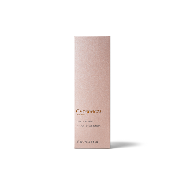 A tall, slim rectangular box for Omorovicza Queen Essence in a pale blush pink color with gold lettering, set against a clean white background.