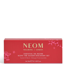 A red rectangular box for NEOM Wellbeing London 'Scent the Season Discovery Set' with gold and pink text and line illustrations, photographed on a plain white background.