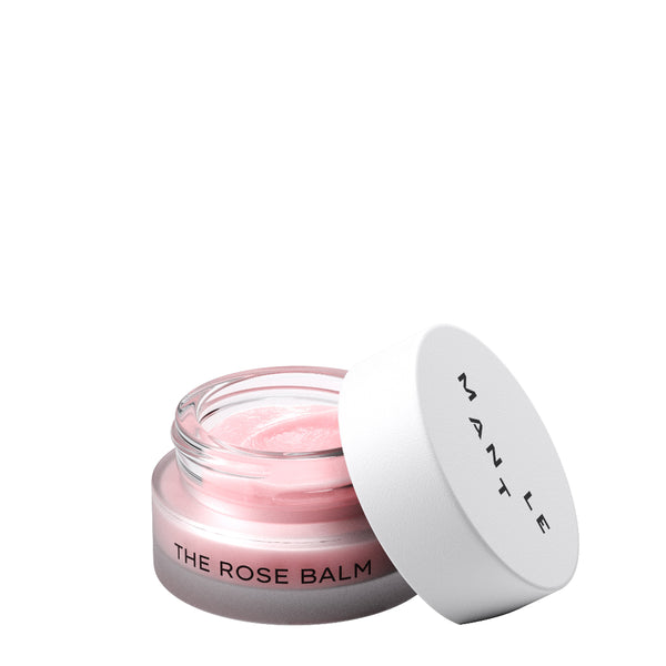 A small clear cosmetic jar labeled 'THE ROSE BALM' containing pale pink balm, shown with its white lid leaning against it on a clean white background. The lid is printed with the brand name 'MANTE'.